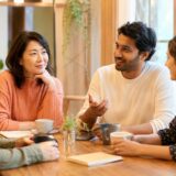 英会話カフェで複数の大人と気軽に英語を話す女性