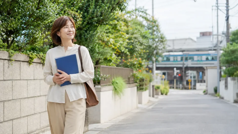藤沢の緑ある街並みを英語のノートを持って歩く大人女性