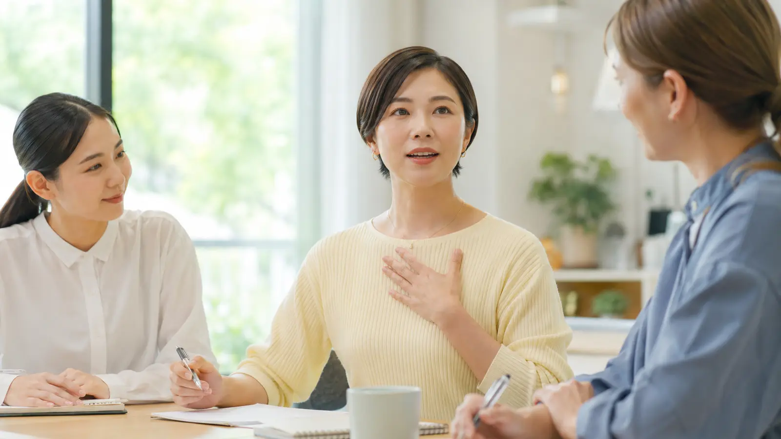 英会話教室で講師と受講生を相手に段階的に話す練習をする大人女性