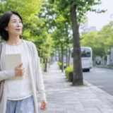 広尾の緑ある住宅街をノートを持って歩く大人女性