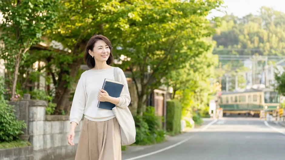 鎌倉の緑ある街並みをノートを持って歩く大人女性