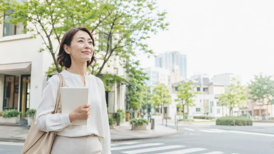 東京都港区の緑ある街並みをノートを持って歩く大人女性