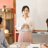 英会話レッスンで人前に立ち、緊張しながら話し始める大人女性