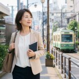 大塚駅と東京さくらトラムの近くを英語のノートを持って歩く大人女性