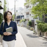代々木上原の緑ある住宅街をノートを持って歩く大人女性