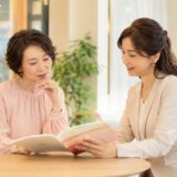 英会話教室の教材を見ながら相談する大人女性