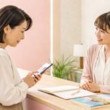 英会話教室の欠席連絡について受付スタッフへ確認する大人女性