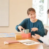 英会話教室でカップと箱を使って前置詞を練習する大人女性初心者