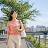 葛飾区の川沿いを歩き週末の英会話教室を検討する大人女性