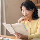 英会話レッスンのノートとカレンダーを見ながら1か月の上達を振り返る大人女性